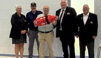 Sarnia-Lambton MPP Bob Bailey holds a lifeguard rescue buoy at the Moore Sports Complex when awarding $1 million for the facility to council members. July, 2025. Image courtesy of the Mooretown Sports Complex Facebook page.